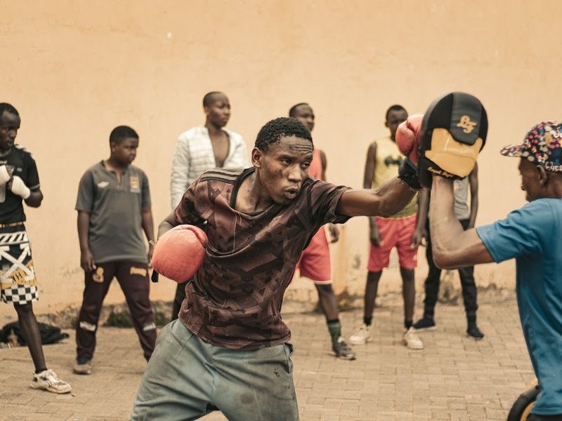Entraînement de boxe en extérieur : un jeune frappe dans des pattes d'ours, entouré du groupe