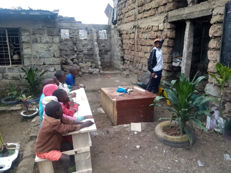 Enfants attablés en extérieur devant un bâtiment, lors d'une activité encadrée